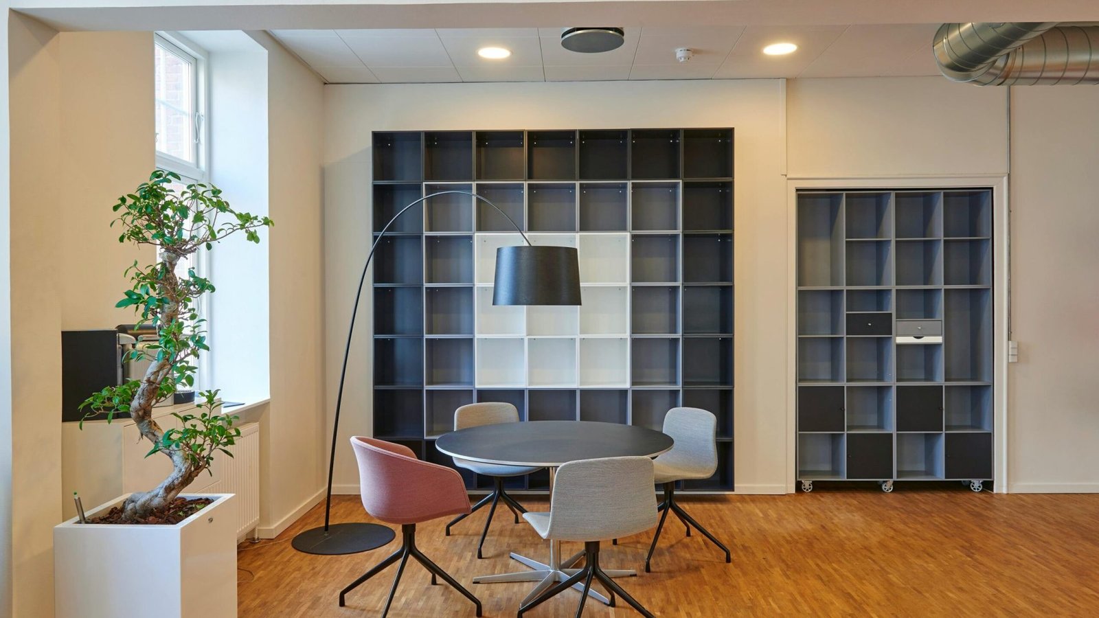 Bright and stylish office space with contemporary furniture and open shelving.